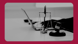 A monochrome image of a legal setting showing a judge's gavel and a scale of justice, with the silhouette of a laptop in the background, symbolising the interplay of law and technology.