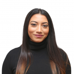 A confident woman with long hair and a black turtleneck smiles subtly against a white background.