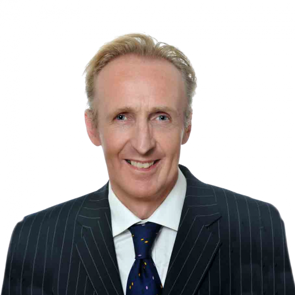 Huw Jones A professional, confident businessman smiling in a formal striped suit with a blue tie against a neutral background.