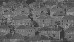 Monochrome urban landscape showing a dense array of similar-looking houses, highlighting architectural uniformity in a residential area.